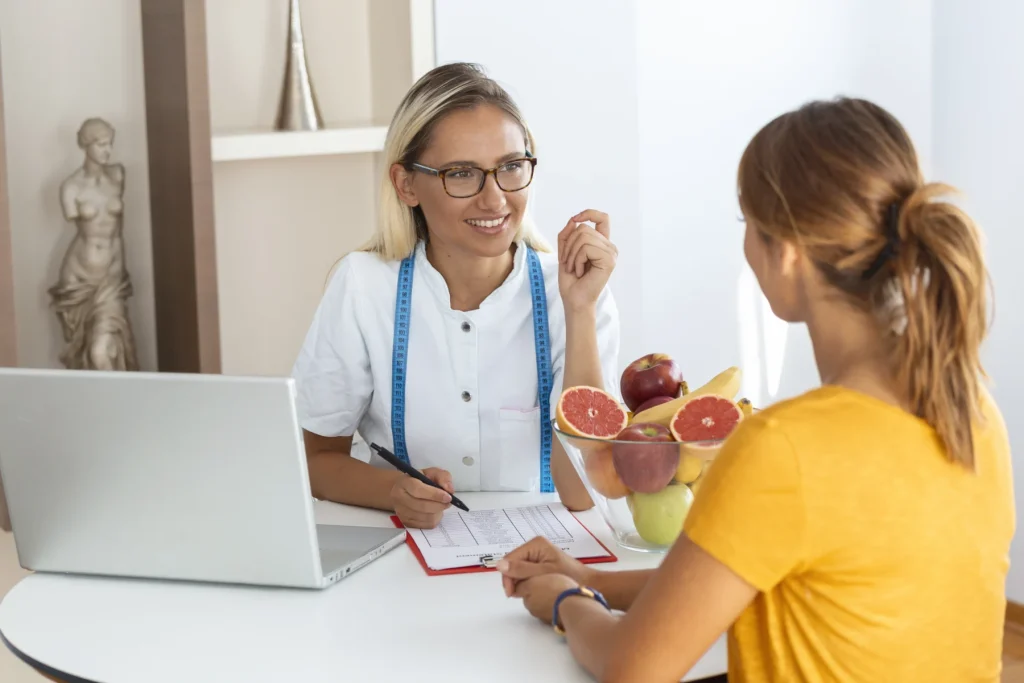 Nutrition practitioner discussing a plan with a visitor across a desk