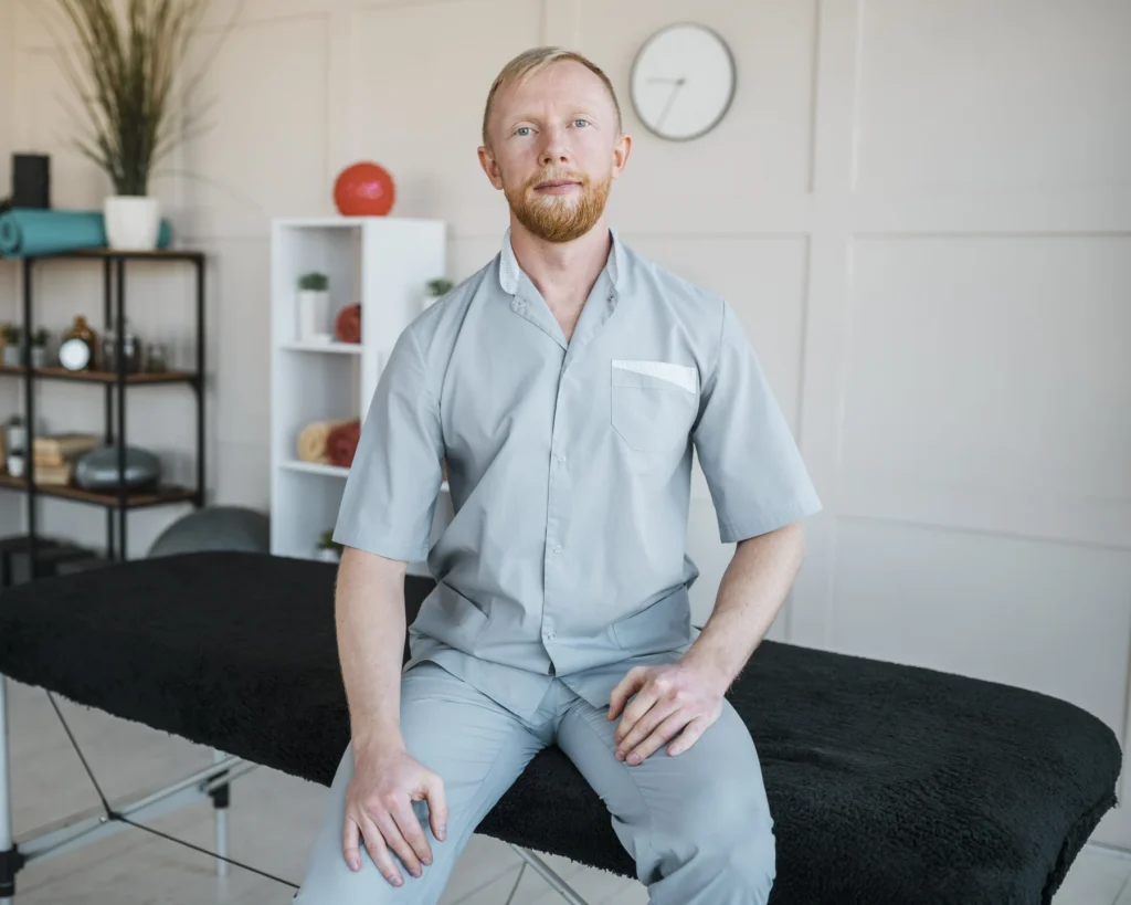 Physiotherapist seated beside exercise equipment in a clinic