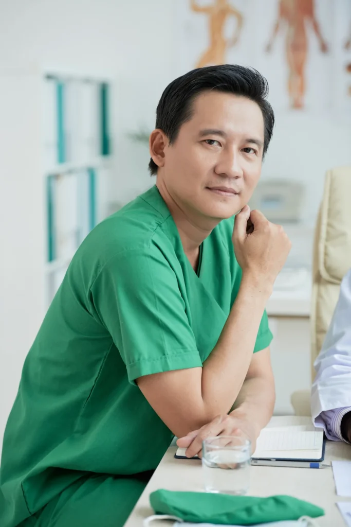 Therapist in green scrubs seated at a clinical desk