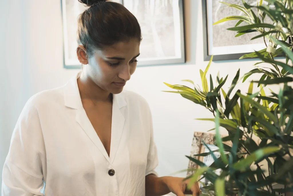 Woman tending houseplants beside a window